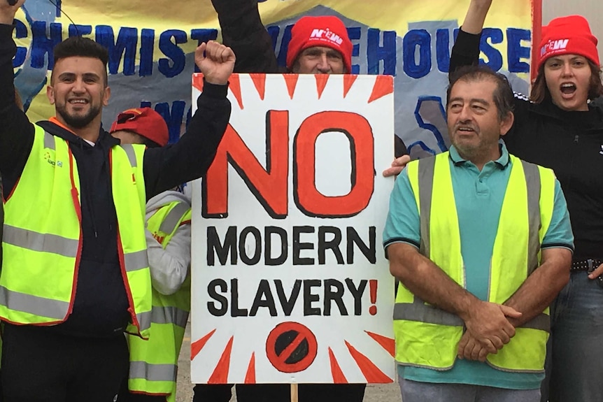 Workers stand with a sign that says 'no modern slavery'.