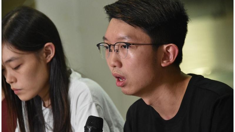 Mr Cheung speaks into a microphone at what appears to be a press conference. He is young with dark hair and glasses.