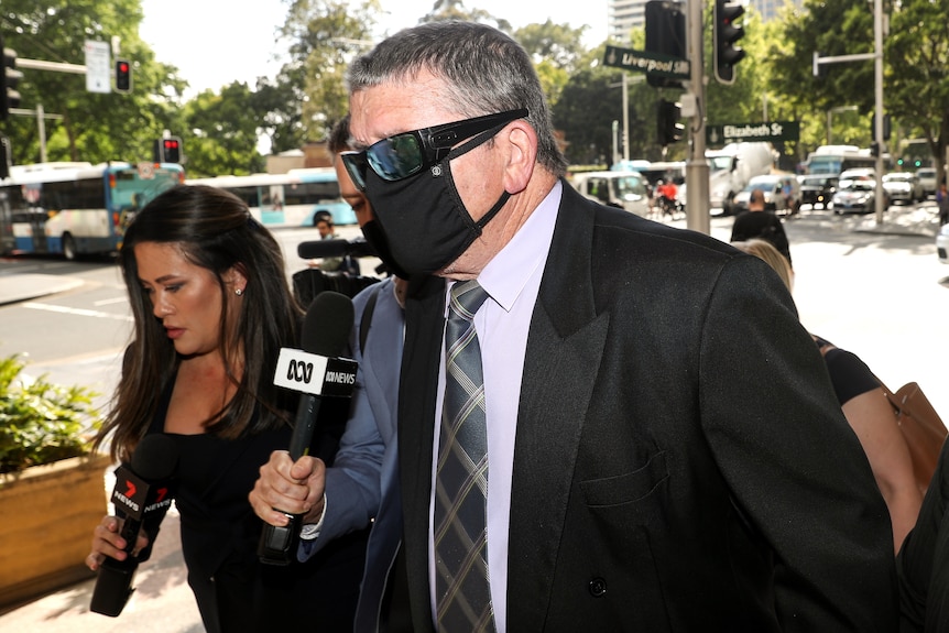A man wearing a mask walks to court