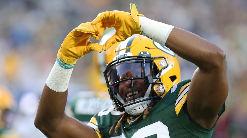 Aaron Jones holds his hands up in a heart sign