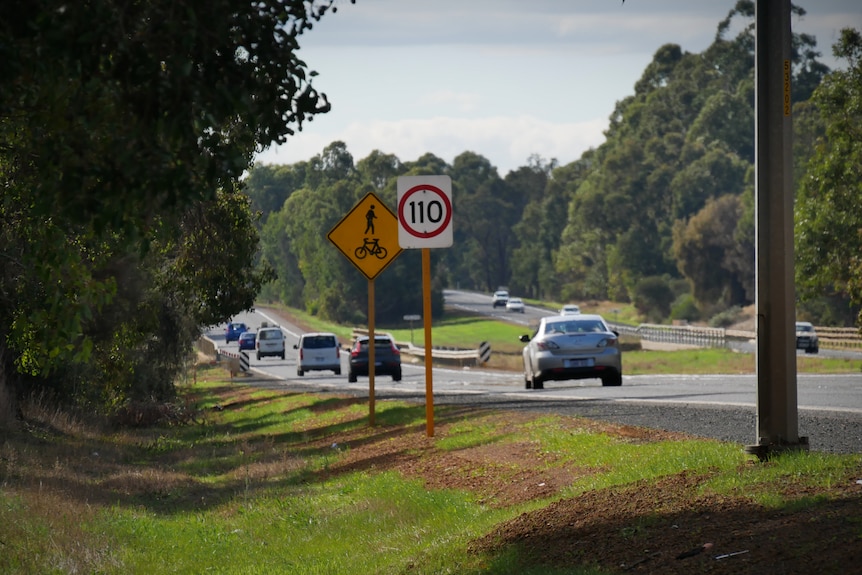 Cars drive down a rural highway