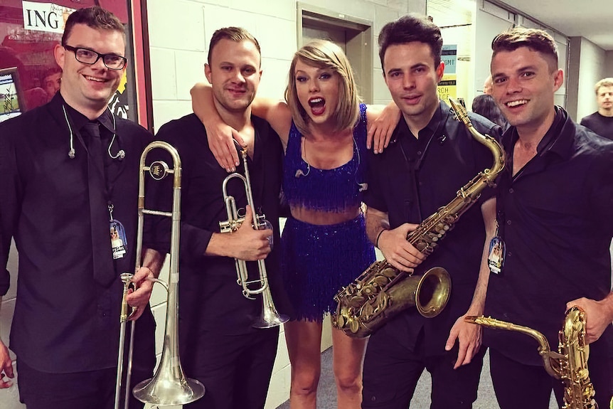 Taylor Swift pictured with four trumpet players