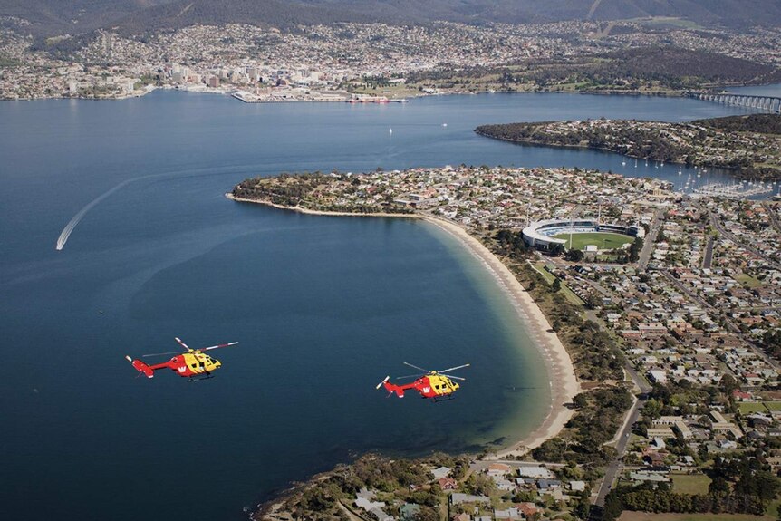 Aerial view of two helicopters flying over Hobart's eastern shore.