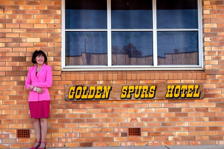 A woman stands outside a pub wearing all pink.
