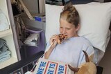 Boy eating pizza while recovering in hospital.