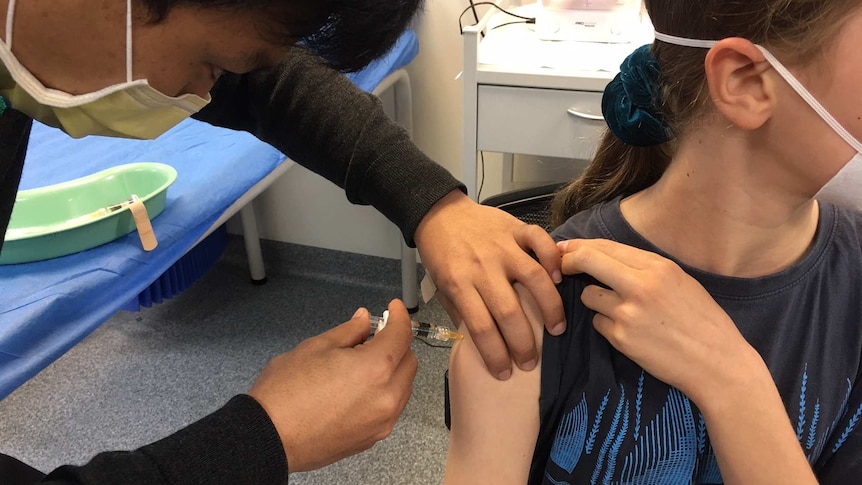 A medical worker injects a girl's arm with the 2020 flu vaccine.