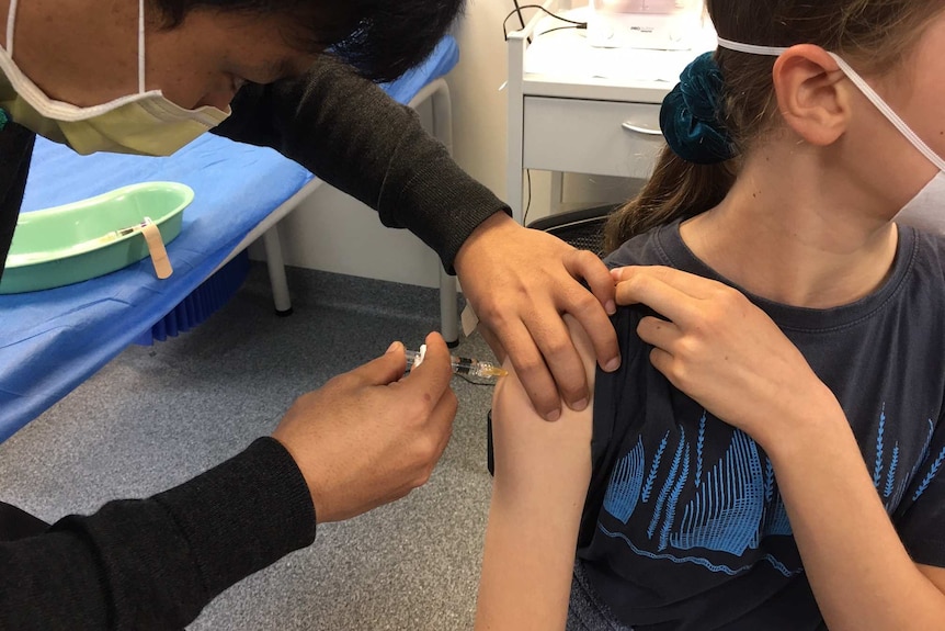 A medical worker injects a girl's arm with the 2020 flu vaccine.