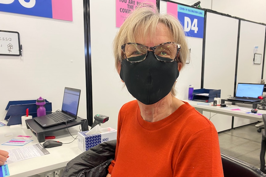 A woman with short blonde hair wearing a mask and glasses. 