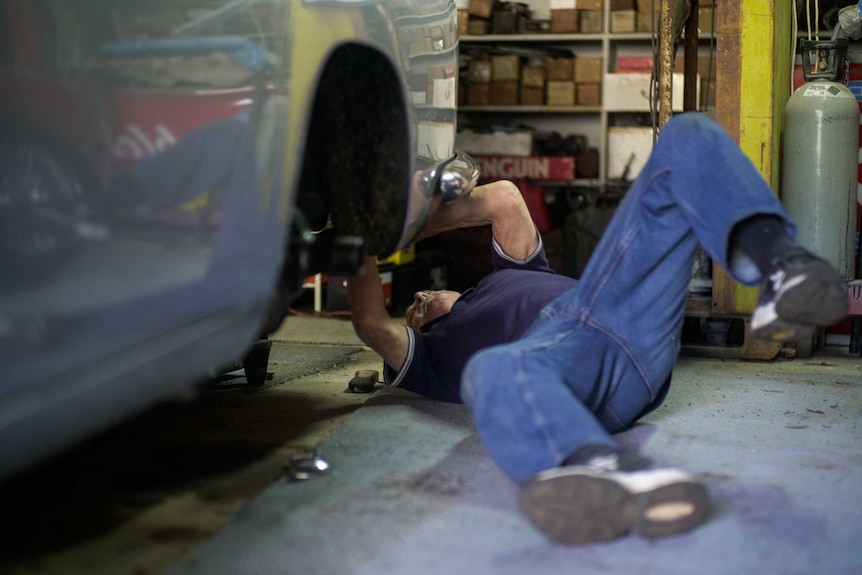 A man working on his vintage Aston Martin DB5 car.