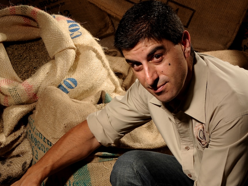 Man with short dark hair, looking inside bag of coffee beans