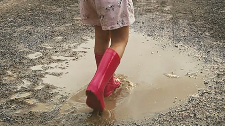 A little girl playing in puddles