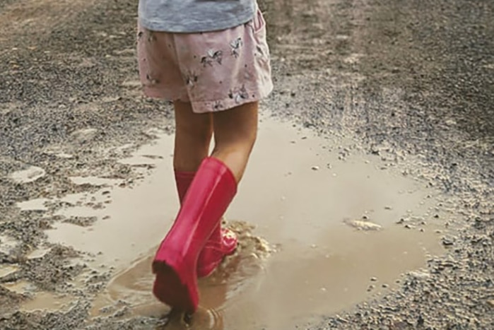 A little girl playing in puddles