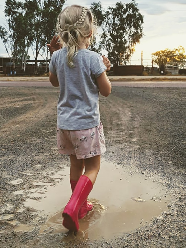 A little girl playing in puddles