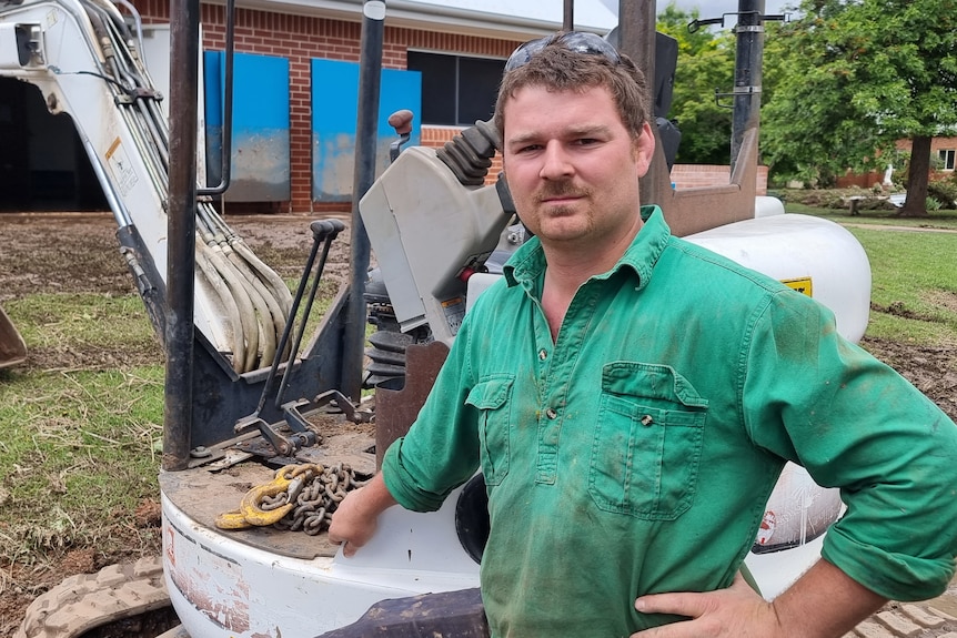 A man stands next to an earth moving vehicle.