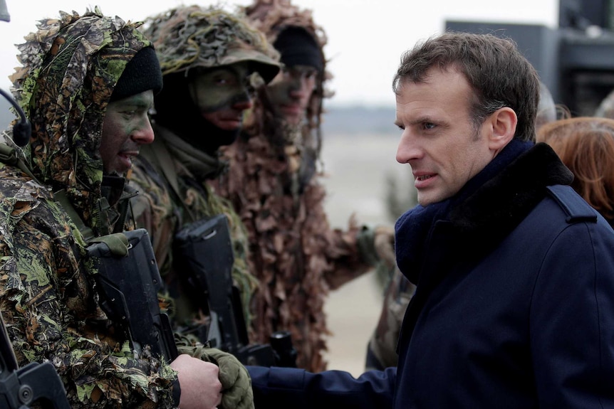 Emmanuel Macron speaks with soldiers wearing military camouflage