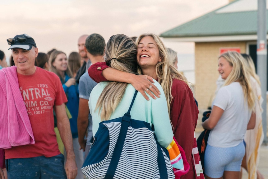 People hugging before an early morning swim at the beach