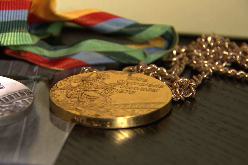 A gold medal from the 1976 Montreal Olympic Games sits next to a silver medal from the 1988 Seoul Games.