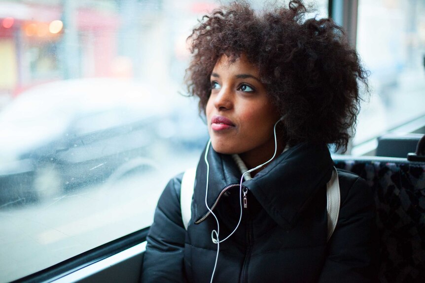 Woman listening to an audiobook with headphones on a bus.