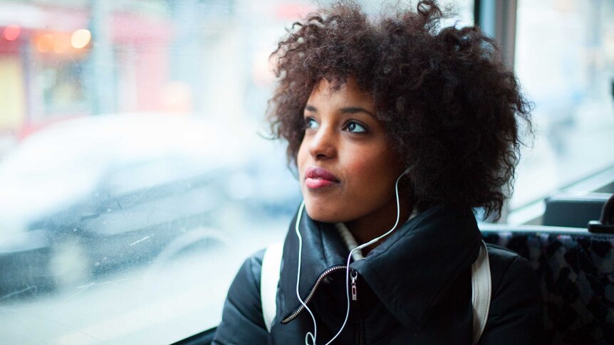 Woman listening to an audiobook with headphones on a bus.