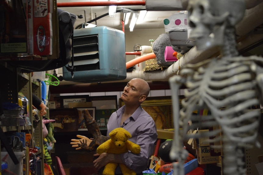 Andrew Best holds a teddy and looks for items in the props department.