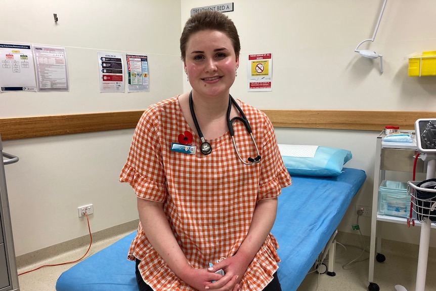 Imogen sitting on a doctor's bed, wearing a stethoscope and name badge.