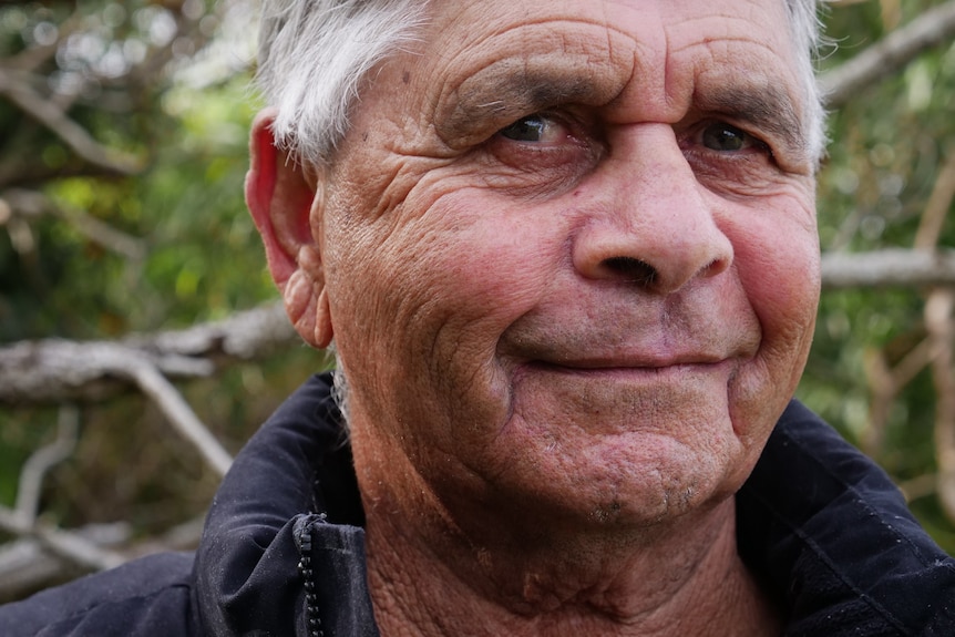 Close-up portrait of a man in his 70s with a warm smile.