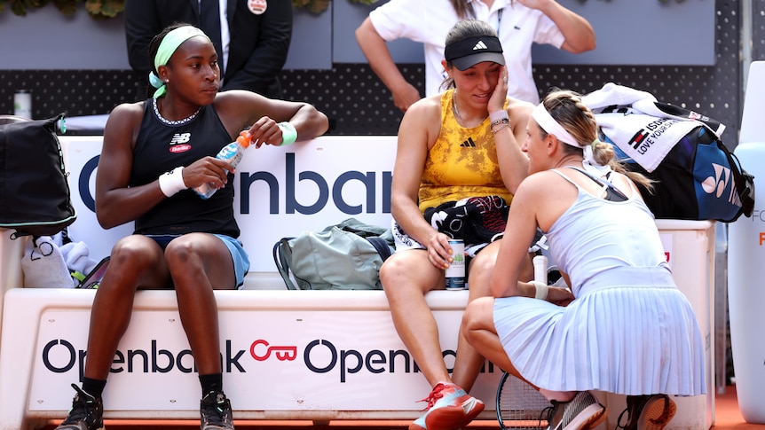 Victoria Azarenka crouches to talk to Coco Gauff and Jessica Pegula at the Madrid Open.