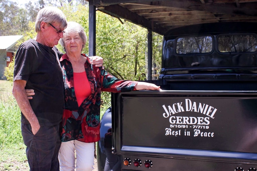 Brian and Cheryl Gerdes, both with grey hair stand near a pickup truck. The tray door is painted with 'Jack Daniel Gerdes.'