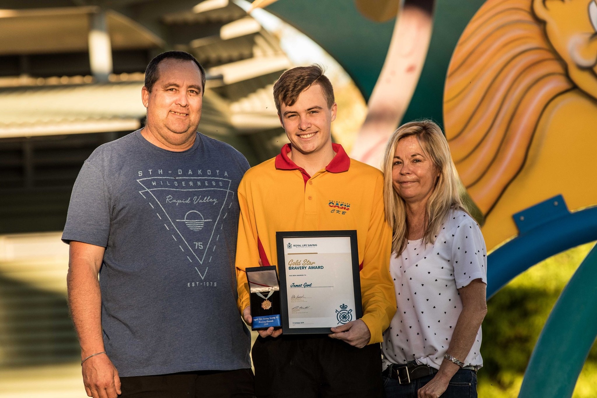 A teenage boy with his parents after receiving an award.  
