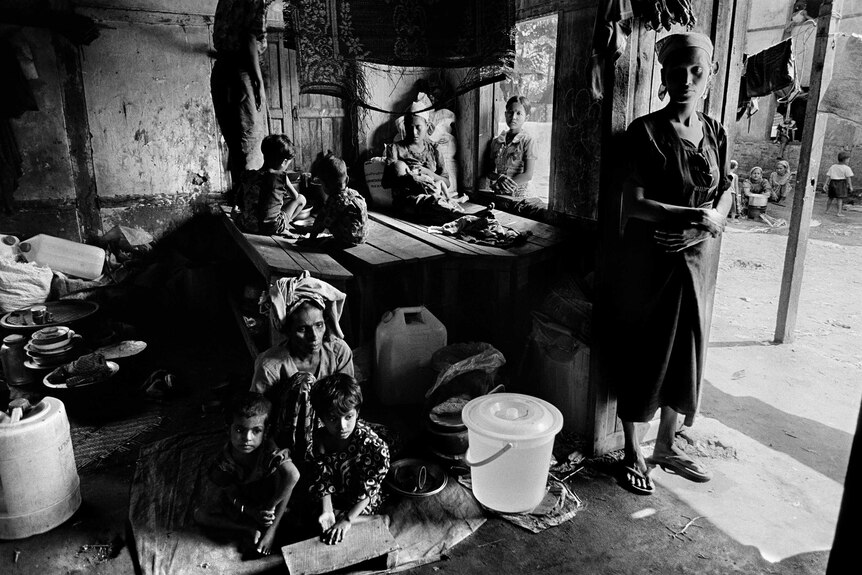 A Rohingya family in a small hut made primarily of bamboo, straw and hay.