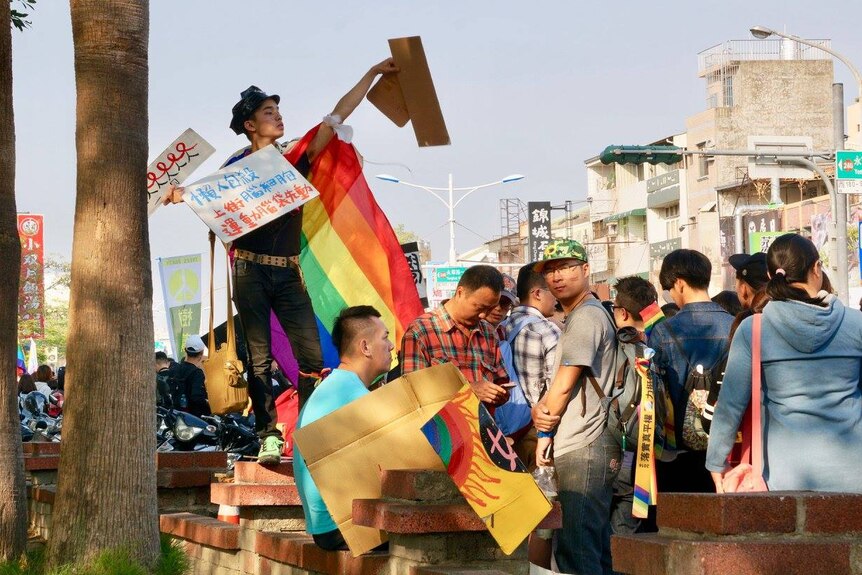 A man stands with a rainbow flag as people gather for the pride march in Taipei, Taiwan.