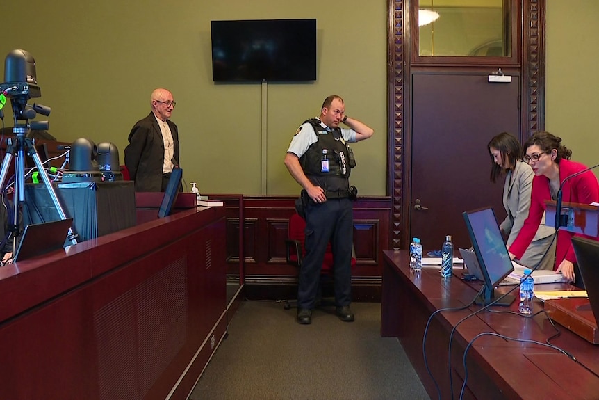 a man standing next to a police man in a room carrying out an inquiry