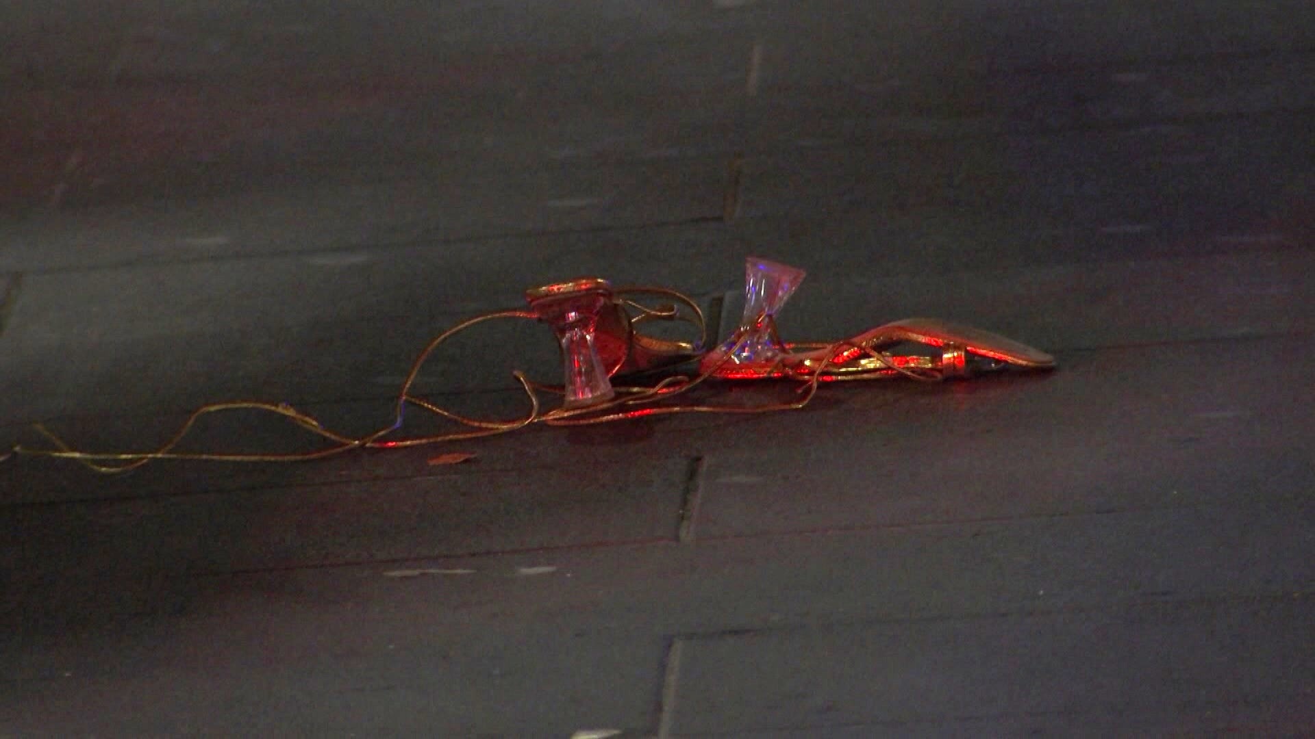 Un par de tacones dorados yacen en la acera de cemento por la noche.