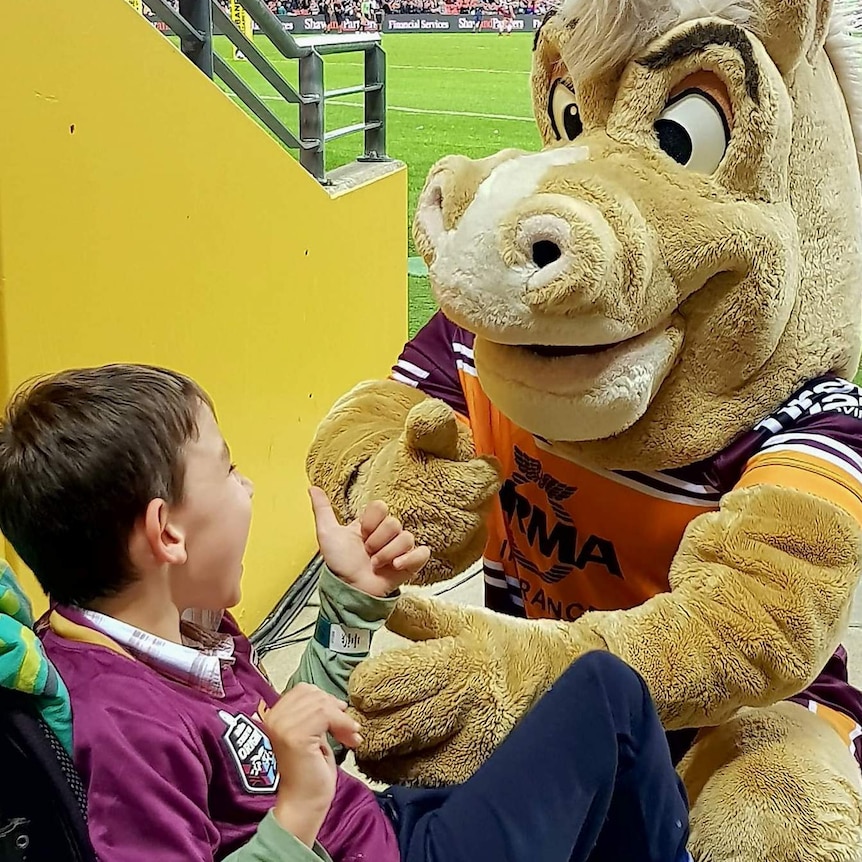 Young boy in a wheelchair with Broncos horse mascot.