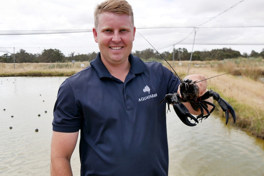 A man stands in front of a dam with a marron.