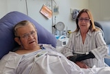 a photo of a man in a hospital bed with his wife sitting next to him 