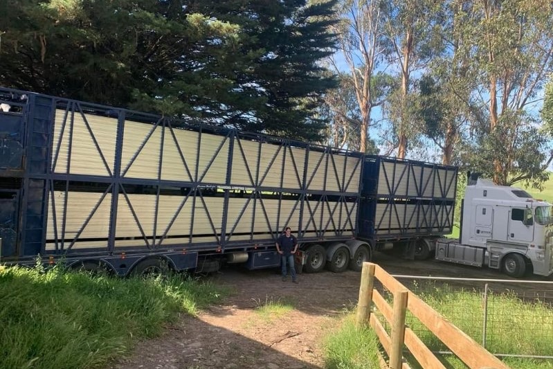 A b-double truck is backed up against a paddock