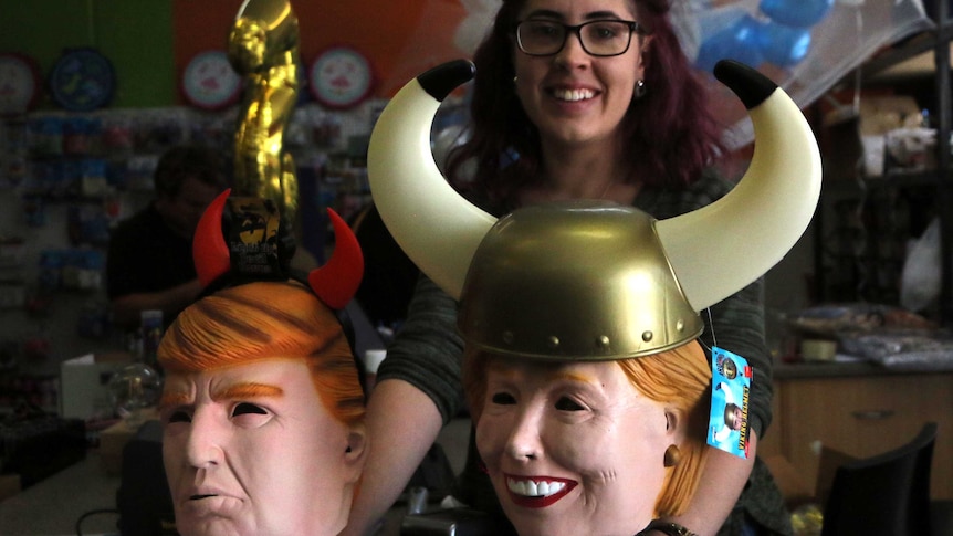 A woman displays masks of Donald Trump and Hillary Clinton.