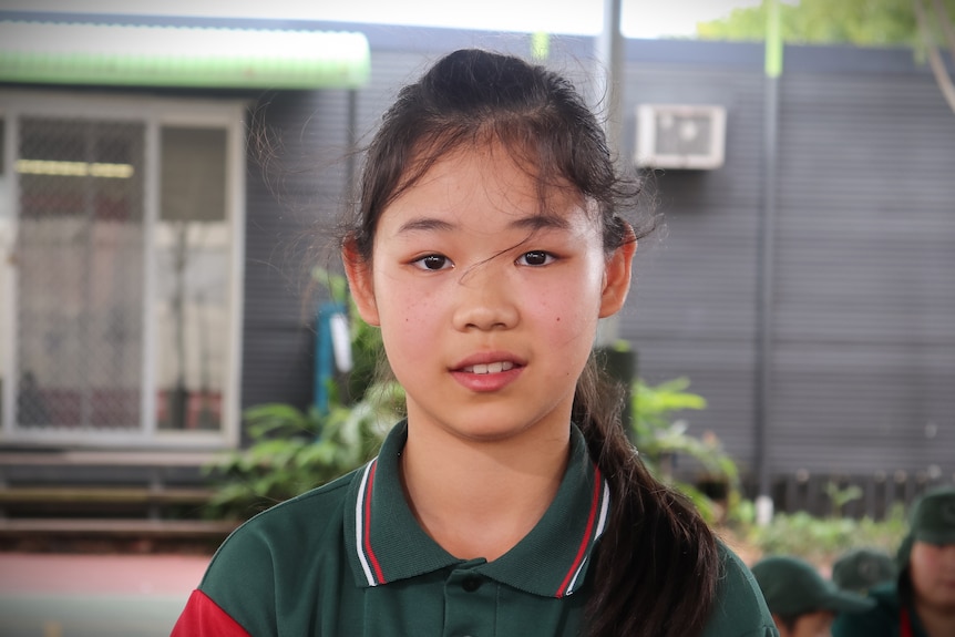 young girl in school uniform looks at camera
