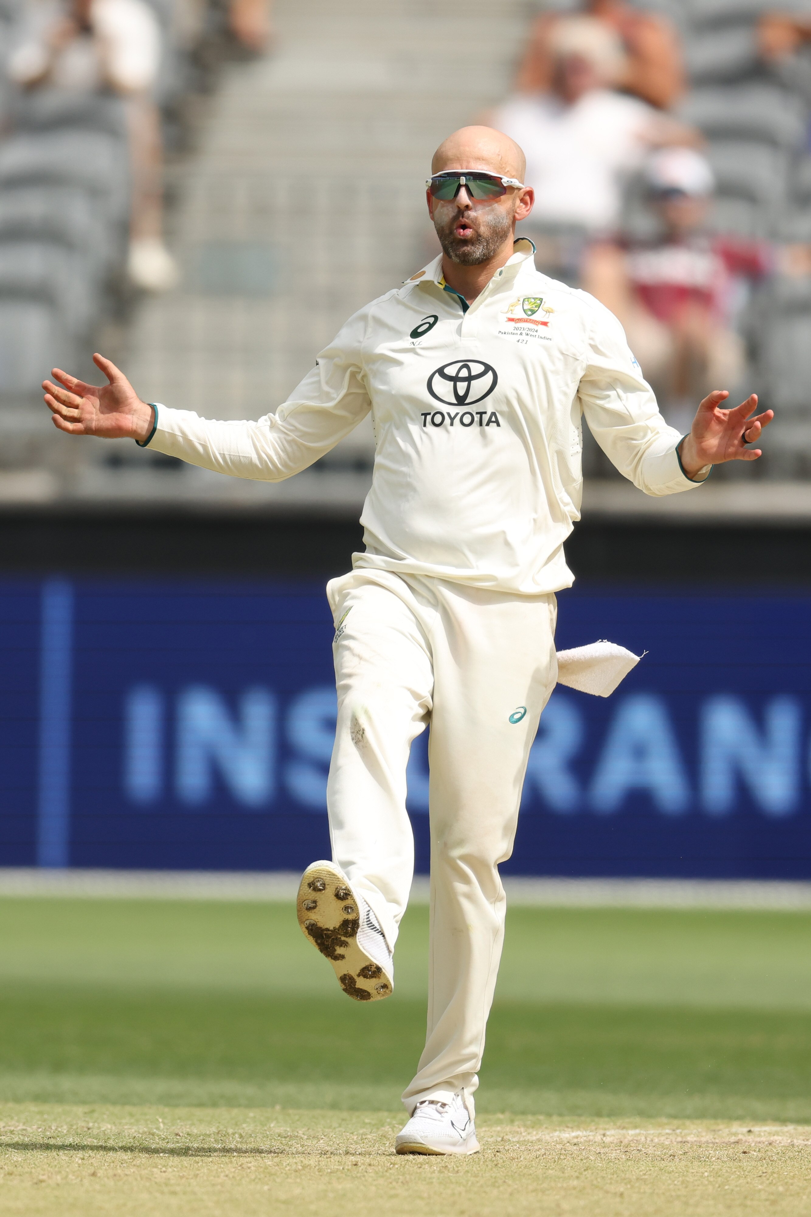 Australia bowler extends his arms, kicks his foot up and purses his lips during a Test.