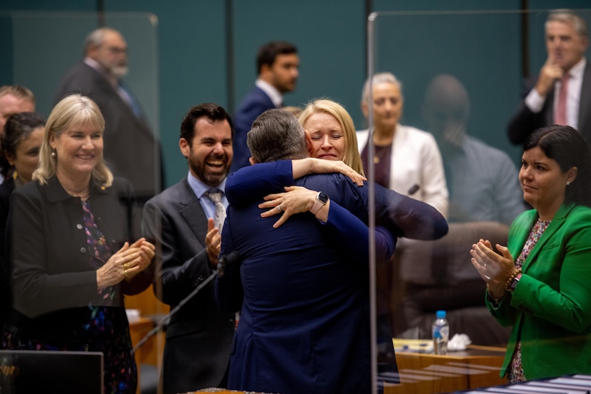 Michael Gunner and Nicole Manison embrace in Parliament as other politicians clap.