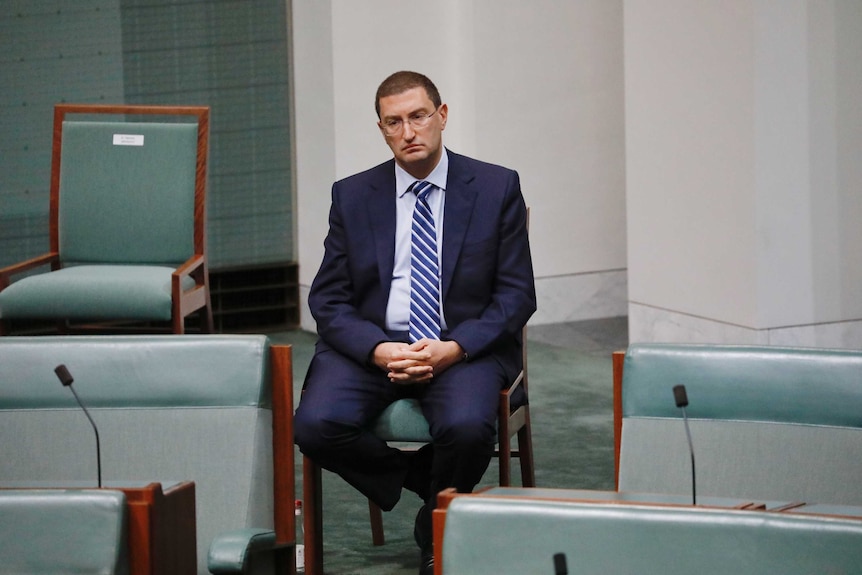 Julian Leeser cuts a lonely figure, sitting on a chair behind the Government back bench.