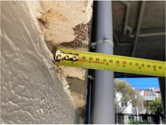 a measuring tape up against the wall showing uneven construction