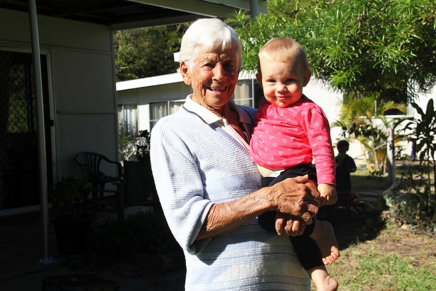 An elderly lady holds a baby.