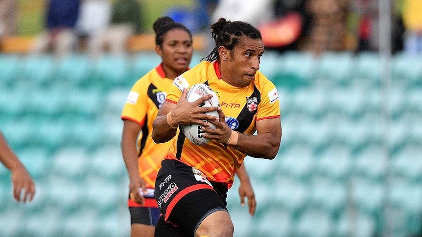 Elsie Albert playing with the PNG Orchids, she is holding the ball and running hard.