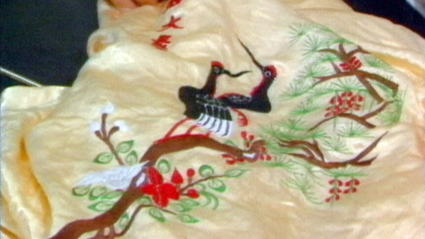 A close up picture of the silk dressing gown, with two birds and a tree embroidered on to it.
