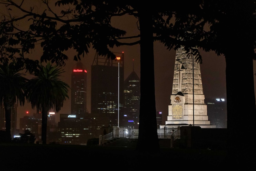 A lit up war memorial with Perth's city skyline in the background