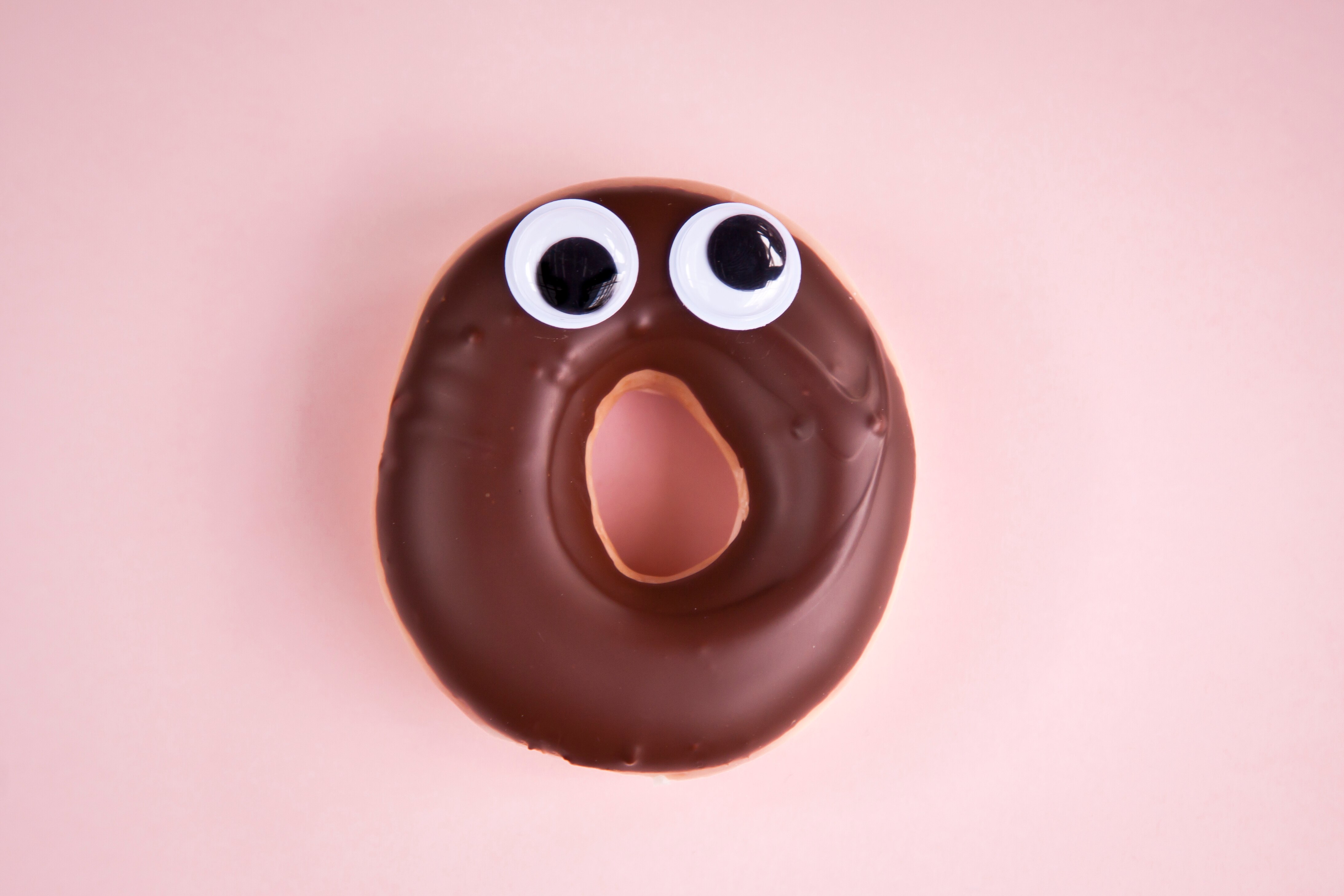 Image of a chocolate covered donut with googly eyes stuck on top.