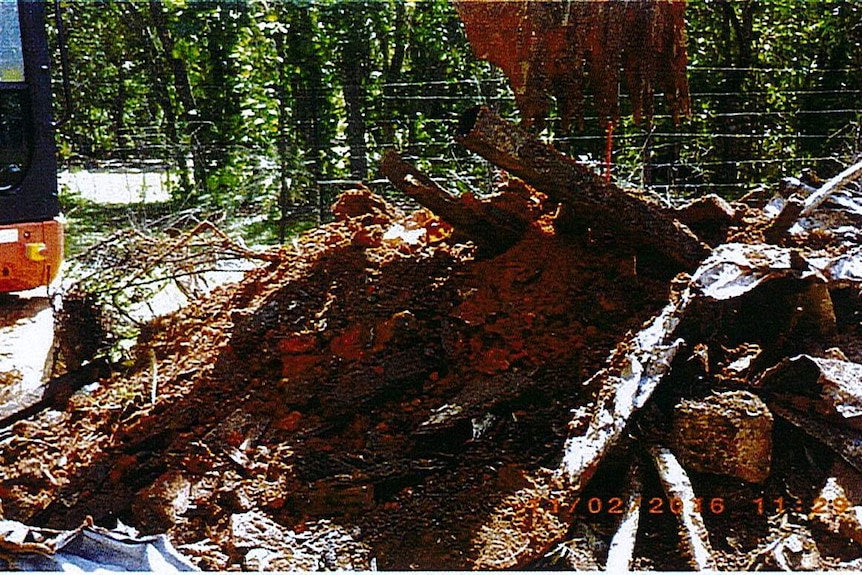 A pile of waste materials in dirty with an excavator to the left incorrectly disposed of by Breakthrough Group.