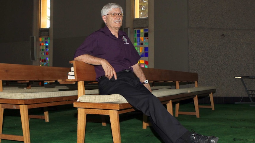 Bishop Gary Nelson sits on a pew in a church.